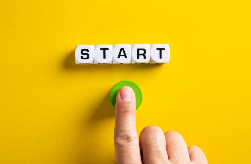 The word start on cubes with a male hand pressing the start button.